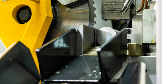 A large circular saw blade is ready to go. A metal rod is about to get cut and slide down a long shaft.