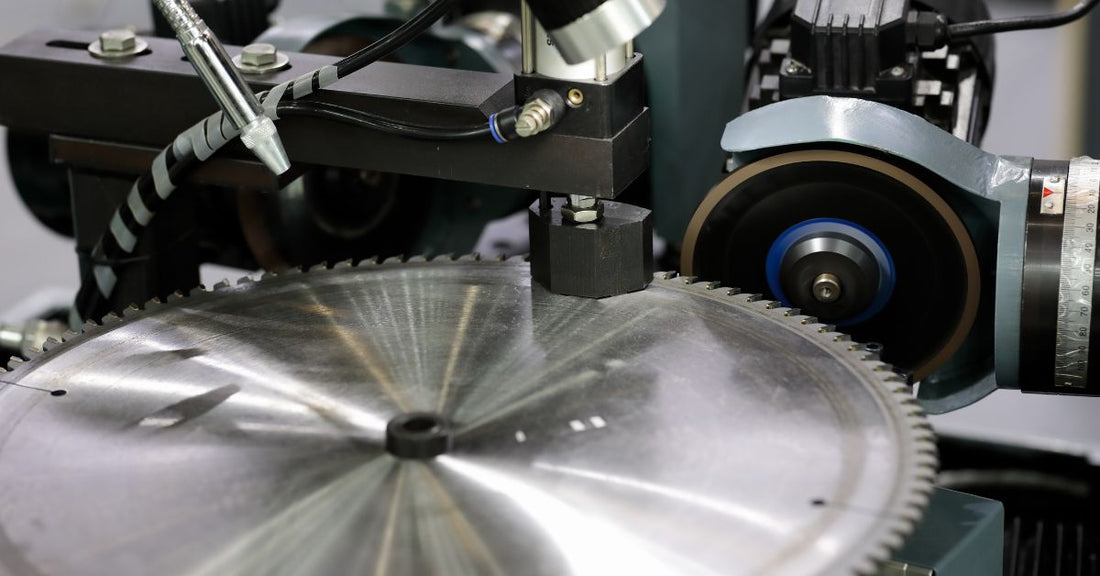 A circular saw blade laying flat in a sharpening machine. The teeth brush up against a sharpener.