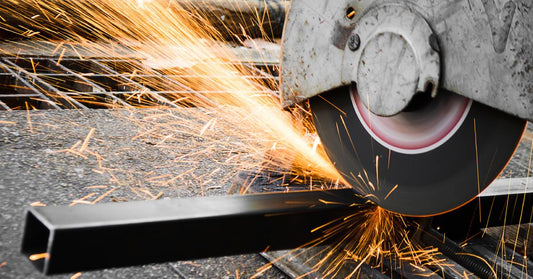 A circular metal saw cuts into a rectangular piece of metal and sends orange sparks flying into the air.