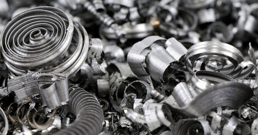 Many curled metal cutting scraps of different sizes and shapes are mixed together, completely covering the surface.