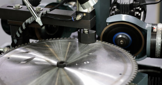 An aluminum-cutting carbide-tipped saw blade sticks up from a saw table covered in a thin layer of dust.
