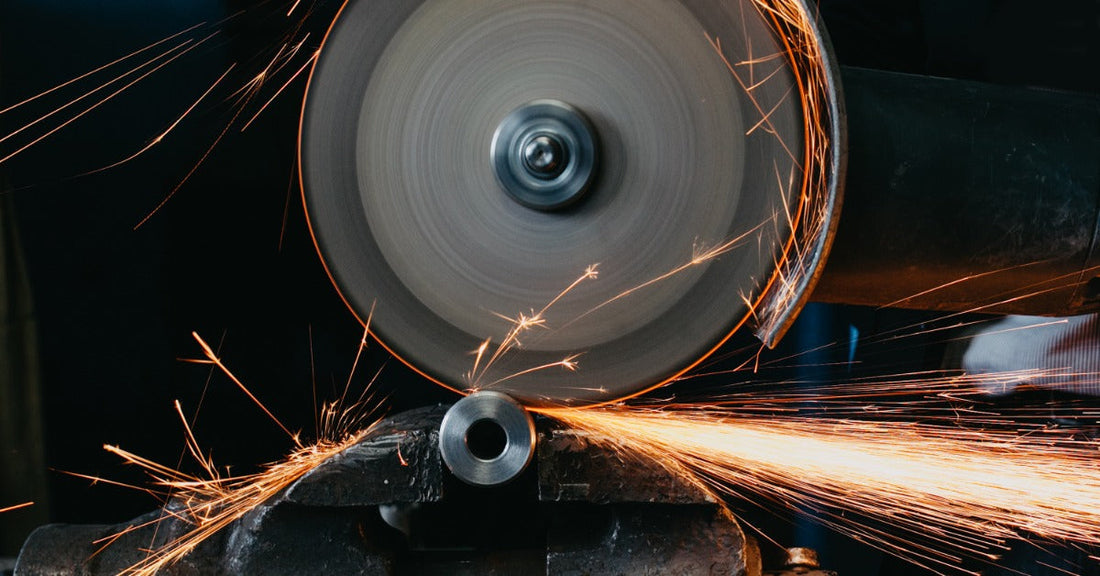 A spinning metal saw blade in the middle of cutting through a piece of metal. Sparks are flying from the blade.